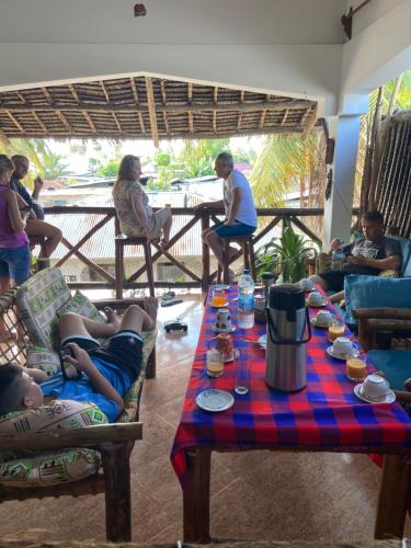 Un groupe de personnes assises autour d'une table dans l'établissement PALM - 2minutes walk to the beach, à Nungwi