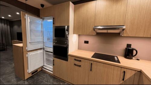 eine Küche mit Holzschränken, einem Kühlschrank und einem Fenster in der Unterkunft Cozy Luxury 2 Bedroom Apartment Near Seaside in Kuwait