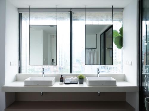 two sinks in a bathroom with two mirrors at Lloyd's Inn Kuala Lumpur in Kuala Lumpur