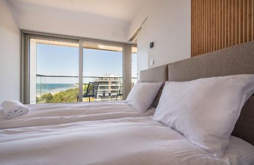 a bedroom with a large bed with a large window at Solaris 711, sea view. in Darłowo