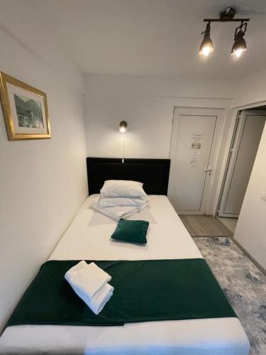 a bedroom with a white bed with a green pillow at Pensiunea Pictorilor in Baia Mare