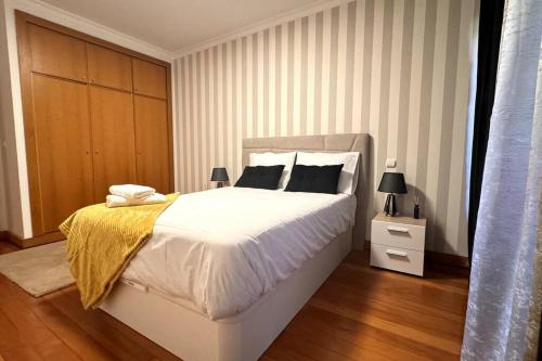 um quarto com uma grande cama branca e piso em madeira em By the Sea IV - Cosy flat no Funchal