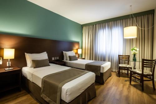 um quarto de hotel com duas camas e uma secretária em Hotel Panamby São Paulo em São Paulo