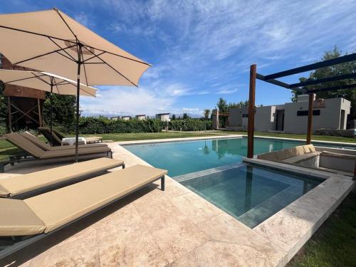 - une piscine avec 2 chaises et un parasol dans l'établissement Agrelo Vines Lodge, à Agrelo