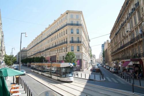 un autobús conduciendo por una calle de la ciudad con edificios en Pied-à-terre cosy pour escale marseillaise, en Marsella