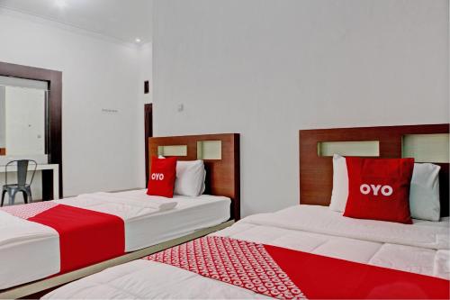 two beds with red pillows in a room at OYO 92945 Guest House Nusa Indah Syariah in Bandar Lampung