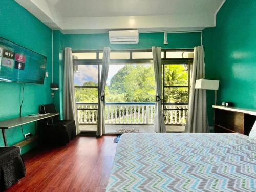 a bedroom with a bed and a window with a balcony at Ngermid Oasis-Spacious Studio Loft W/ Garden Views in Koror
