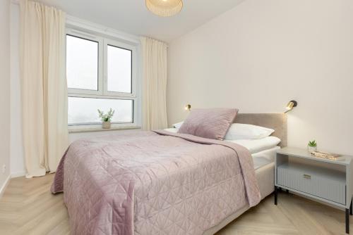 a white bedroom with a bed and a window at Warsaw Skyline Apartments by Renters in Warsaw