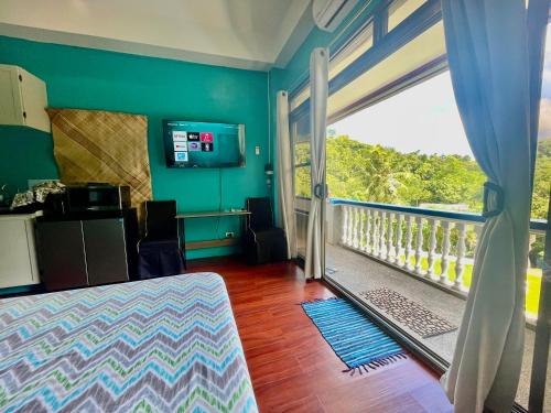 a room with a balcony with a bed and a window at Ngermid Oasis-Spacious Studio Loft W/ Garden Views in Koror