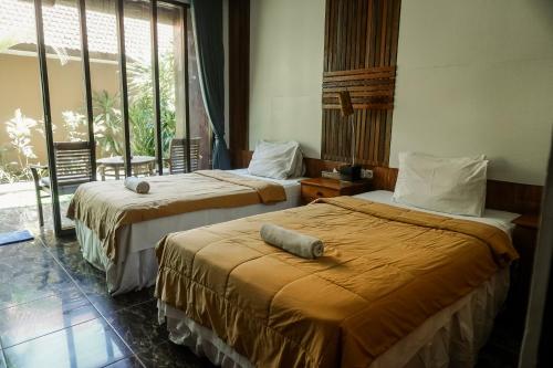 two beds in a room with a window at Olas homestay bali in Uluwatu