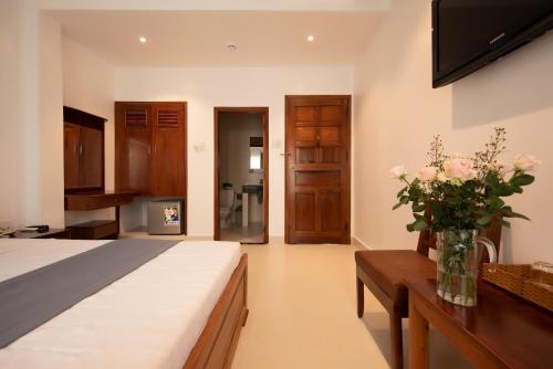 - une chambre avec un lit et un vase de fleurs sur une table dans l'établissement Ngọc Châu Hotel, à Hô-Chi-Minh-Ville
