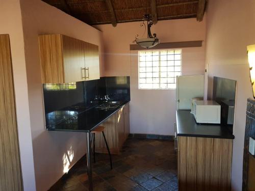 uma cozinha com bancadas pretas e um frigorífico em Lagai Roi Guesthouse em Boshoek