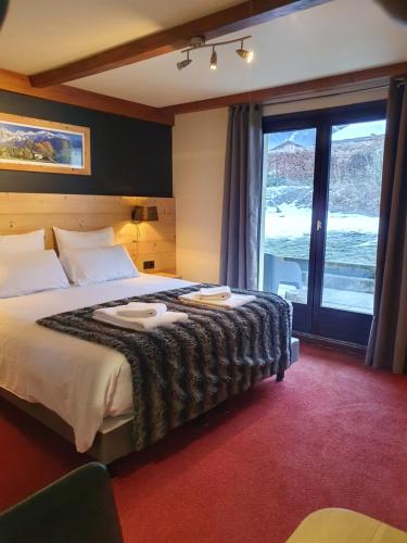 a hotel room with a large bed and a large window at Chalet Hôtel du Bois in Les Houches
