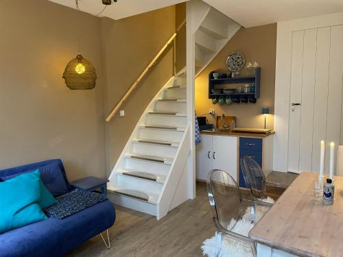 sala de estar con escalera y sofá azul en Het Heertje, en Den Hoorn