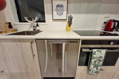 La cuisine est équipée d'un réfrigérateur en acier inoxydable et d'un évier. dans l'établissement Lovely Brand New Home, à Christchurch