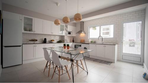a white kitchen with a table and chairs in it at Casa Memorial Miguel Faial - Relaxing Patio in Ponta Delgada