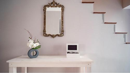 a white table with a mirror and a vase with flowers at Casa Memorial Miguel Faial - Relaxing Patio in Ponta Delgada