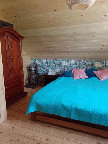 1 dormitorio con cama azul y pared de madera en Domek nad Stawem Siemuszowa en Tyrawa Wołoska