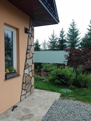 a building with a stone pillar with a green roof at Domek nad Stawem Siemuszowa in Tyrawa Wołoska