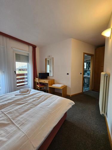 Sarche di CalavinoにあるHotel Idealの大きなベッドとデスクが備わるホテルルームです。