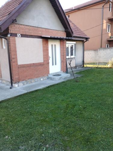 a house with a garage and a grass yard at Kućica LaMa-Кућица ЛаМа in Mali Mokri Lug