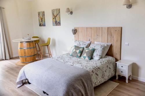1 dormitorio con 1 cama con cabecero de madera y mesa en Clos de la source, en Saint-Martin-du-Bois