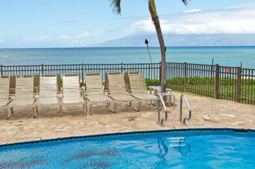 una piscina con sedie e l'oceano sullo sfondo di Hololani Resort a Kahana