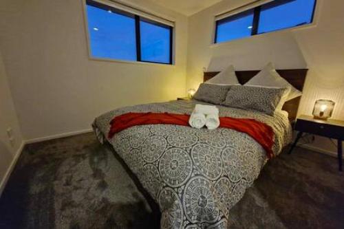 a bedroom with a large bed with two towels at Lovely Brand New Home 26 in Christchurch