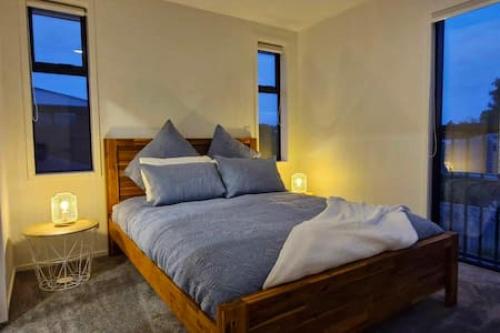 a bedroom with a large bed with blue pillows at Lovely Brand New Home 26 in Christchurch