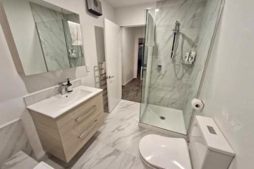 a bathroom with a shower and a toilet and a sink at Lovely Brand New Home 26 in Christchurch