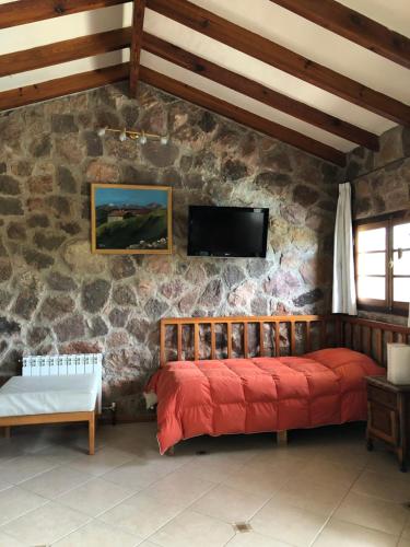 um quarto com uma cama vermelha numa parede de pedra em casas lago san roque em Villa Carlos Paz