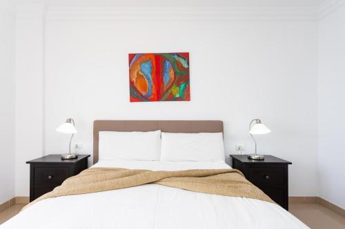a bedroom with a bed with two night stands and a painting at Home2Book Comfy Apartment With Ocean Views Radazul in Radazul