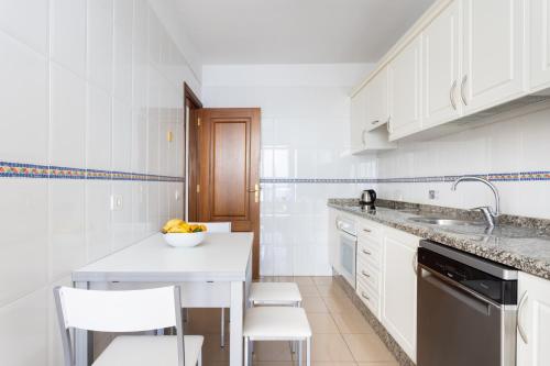 a white kitchen with white cabinets and a counter top at Home2Book Comfy Apartment With Ocean Views Radazul in Radazul