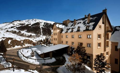 a large building with snow on it in front of a mountain at Eurostars Royal Tanau in Baqueira-Beret