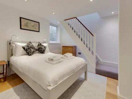 a bedroom with a white bed and a staircase at Pass the Keys Centrally located modern and spacious 3 Bed terrace in Cambridge