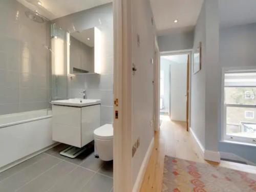 a white bathroom with a toilet and a sink at Pass the Keys Centrally located modern and spacious 3 Bed terrace in Cambridge
