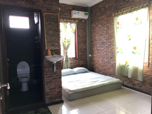 Habitación con cama y lavabo en una pared de ladrillo. en Bua Guest House, en Medan