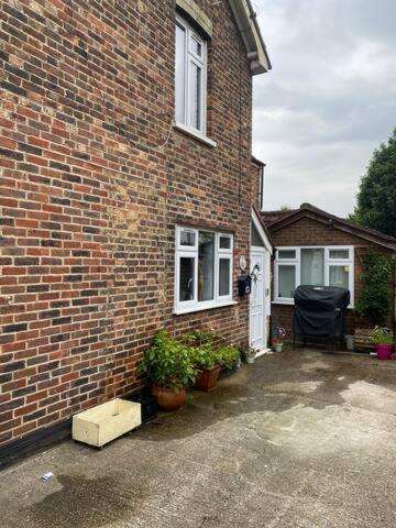 a brick house with two windows and two potted plants at Pond Cottage in Purley