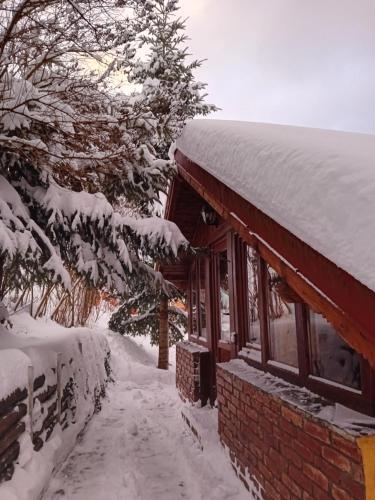 a snow covered house with a snow covered roof at La Gabi in Azuga