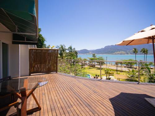 a deck with a table and an umbrella and the ocean at Hotel Velas do Engenho in Ilhabela