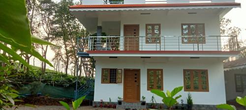 a white house with a balcony on top of it at Silver home stay vagamon in Vagamon