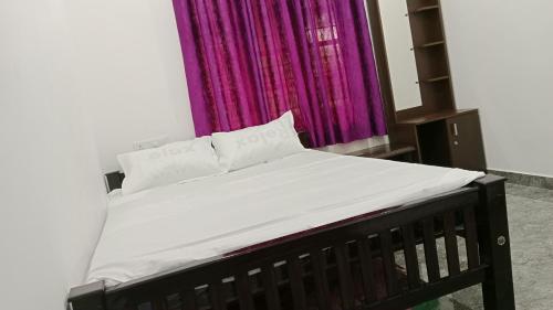 a bed in a room with a purple curtain at Silver home stay vagamon in Vagamon