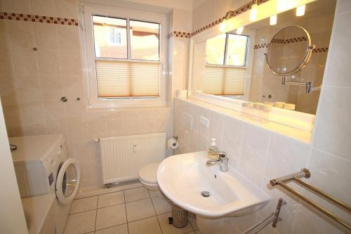 La salle de bains est pourvue d'un lavabo, de toilettes et d'un miroir. dans l'établissement Apartmentvermittlung Mehr als Meer - Objekt 60, à Niendorf