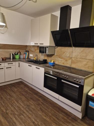 a kitchen with white cabinets and black appliances at VICTORY GuestHouse - Handwerker Pension in Bielefeld