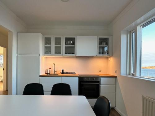 a kitchen with white cabinets and a table and a window at Apartment Fernsicht in Borgarnes