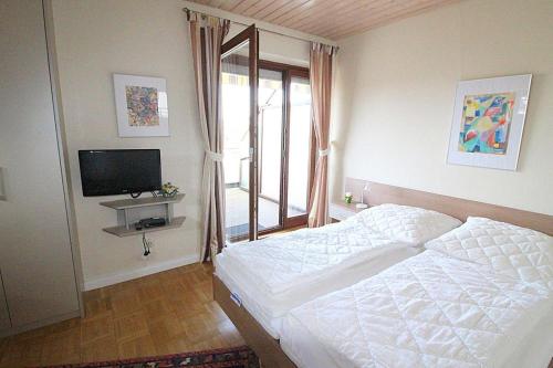a bedroom with a white bed and a television at Obj. 45* kleine, moderne FeWO 2 Pers. - nur 300 m zum Strand, W-LAN, Balkon in Häven