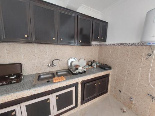 eine Küche mit schwarzen Schränken und einem Waschbecken in der Unterkunft Tanja balya 21 in Tangier