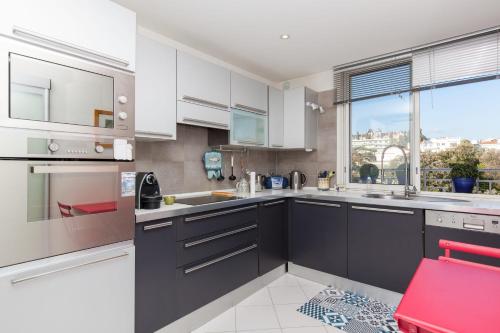 une cuisine avec des placards blancs et une grande fenêtre dans l'établissement 2-Br apartment by the beaches Magical sea view, à Cannes