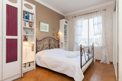 une chambre avec un lit blanc et une fenêtre dans l'établissement 2-Br apartment by the beaches Magical sea view, à Cannes