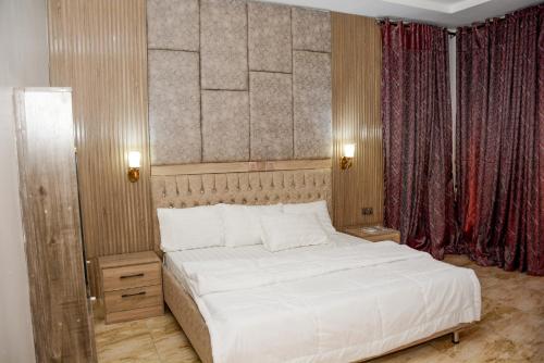 1 dormitorio con 1 cama grande con sábanas blancas en Dabras Homes, en Kaduna